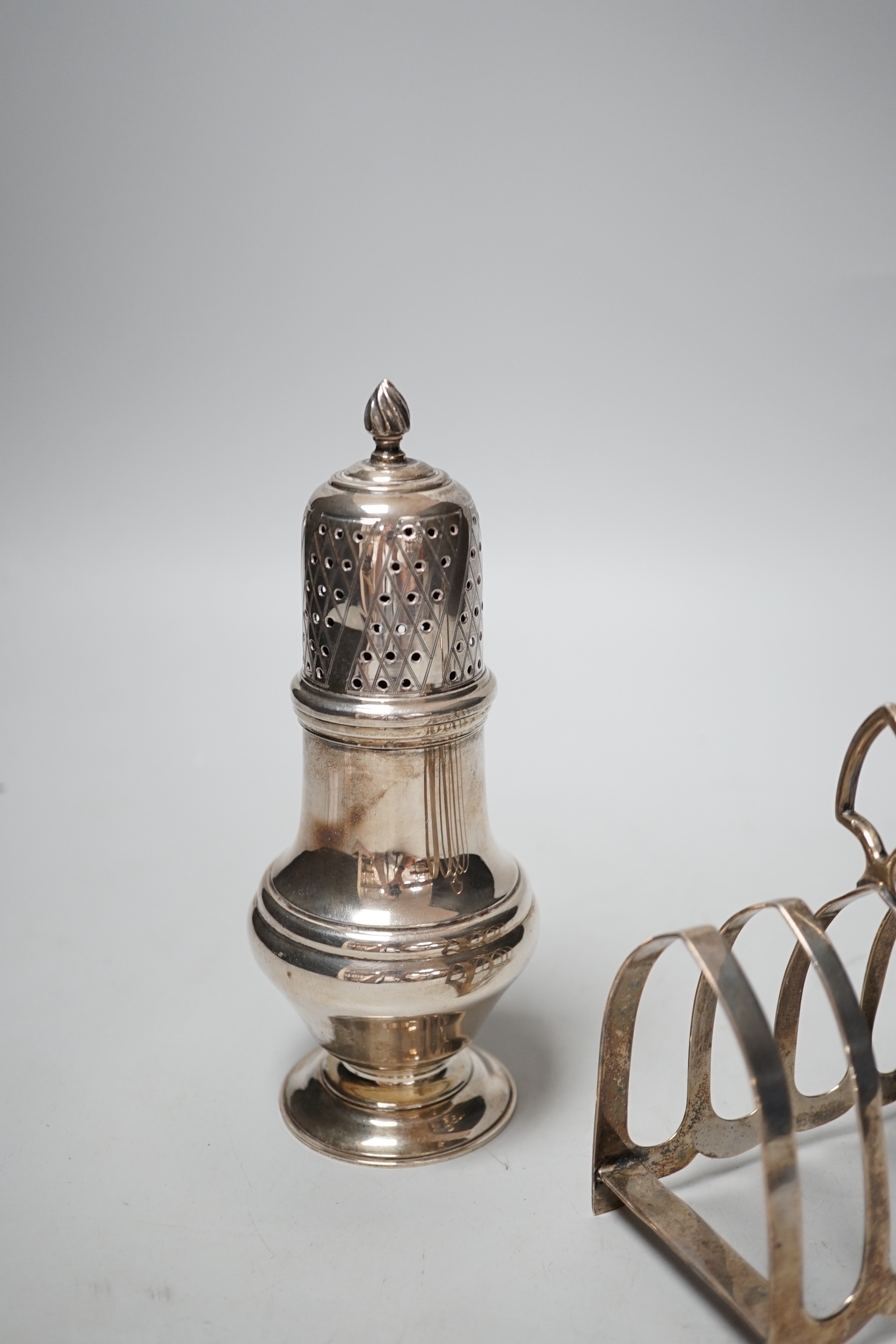 A modern silver sugar caster, 16.5cm and a George V silver toast rack, 8.7oz.